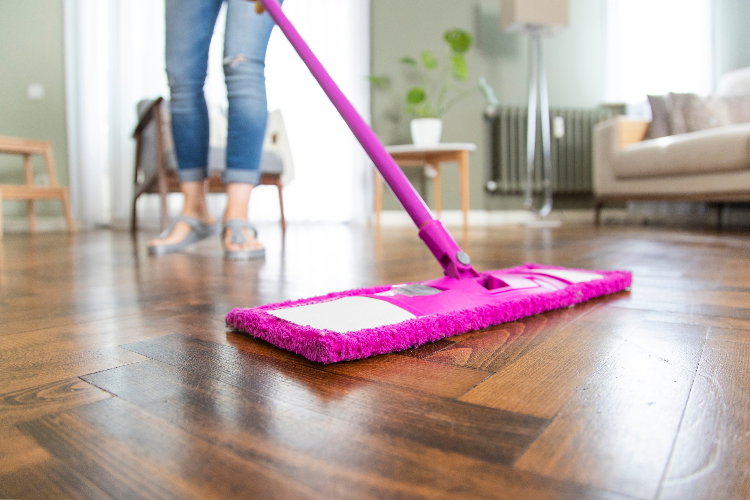 Homeowner gently mopping a Restoring Classic Herringbone dark-oak parquet floor in a Rainham living room, highlighting the rich chevron pattern and post-refinish sheen.