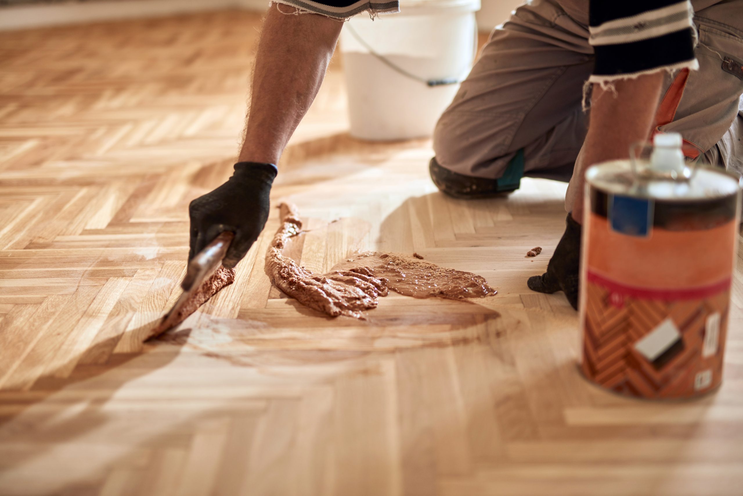 Craftsman applying resin gap-filler while Restoring Classic Herringbone oak parquet flooring in a Rainham home.