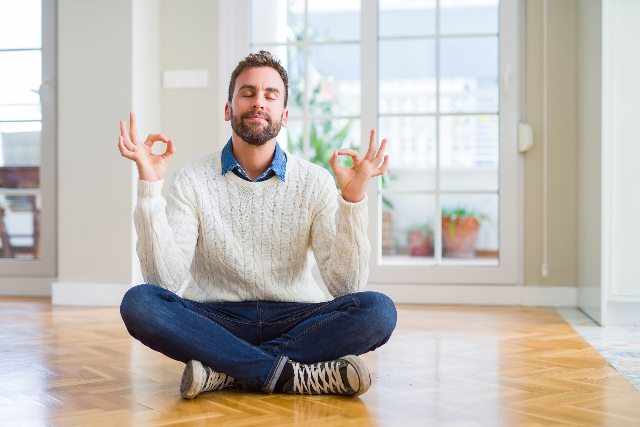 Relaxed homeowner meditating on a freshly finished oak herringbone parquet floor in Rainham after Restoring Classic Herringbone.