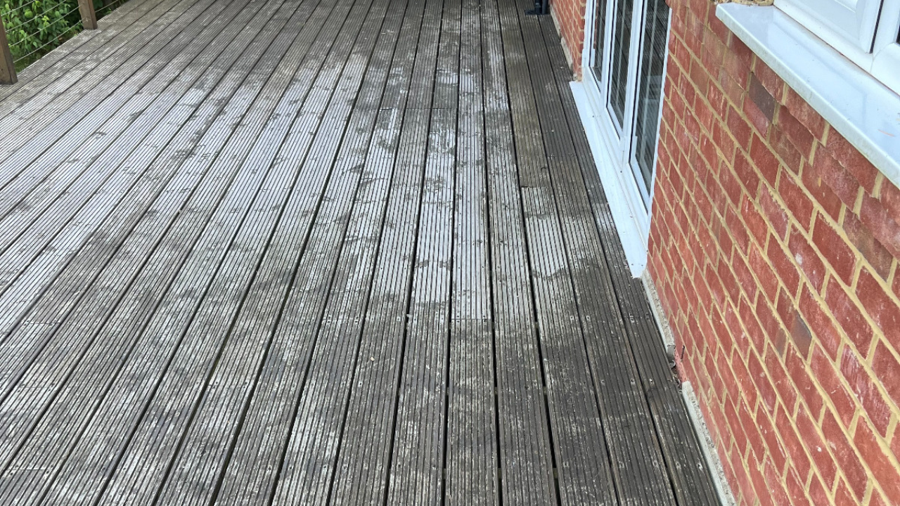Deck Sanding in Rainham – weathered grooved softwood garden decking before restoration beside a red brick house.