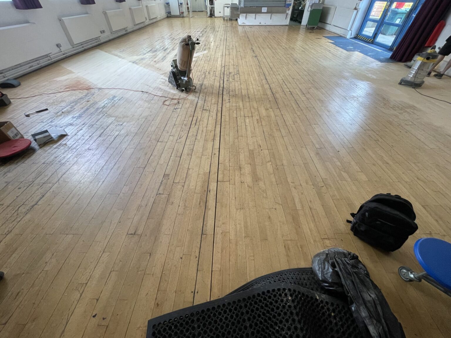 Commercial Floor Sanding in Rainham – maple strip hardwood school hall floor being sanded with professional floor sander for a durable, high-traffic finish.