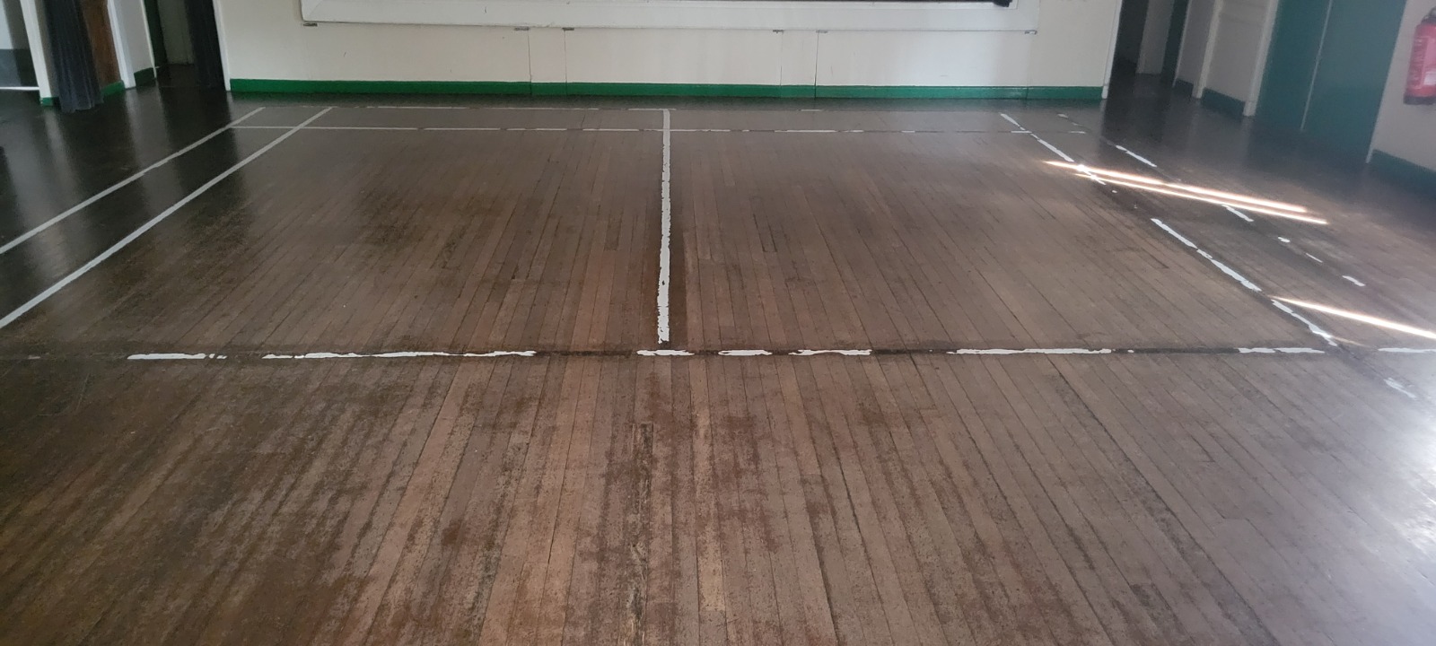 Commercial Floor Sanding in Rainham – worn maple strip hardwood sports hall floor before sanding, showing heavy traffic marks and faded finish on a commercial venue floor.